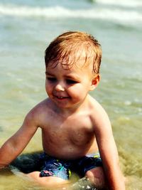 Close-up of baby boy sitting on shore in water at beach