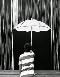 Rear view of man relaxing in front of built structure