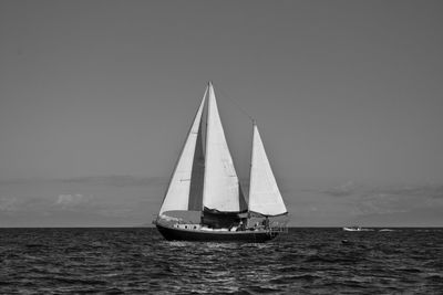 Sailboat sailing on sea against sky in black and white