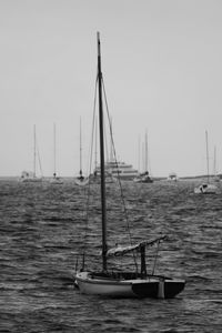 Sailboats moored in sea against clear sky