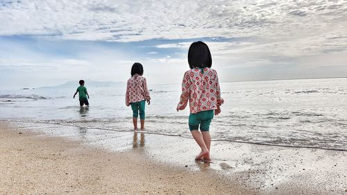 Rear view of siblings standing on beach