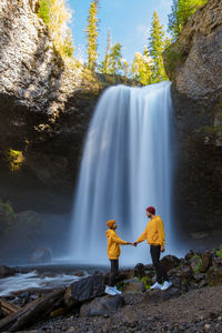 Rear view of woman standing against waterfall