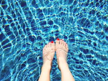 Low section of woman standing in swimming pool