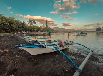 Boats moored on shore against sky