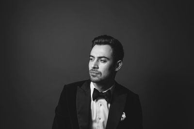 Portrait of young man standing against black background