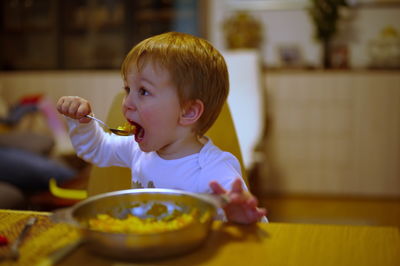 Little toddler sitting at the table and eating