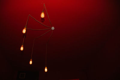 Low angle view of illuminated light against red wall