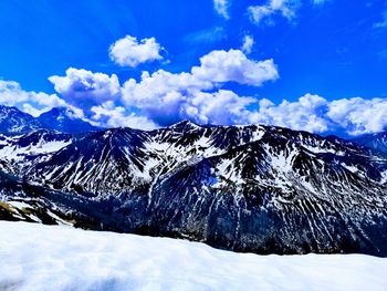 Scenic view of snowcapped mountains against blue sky