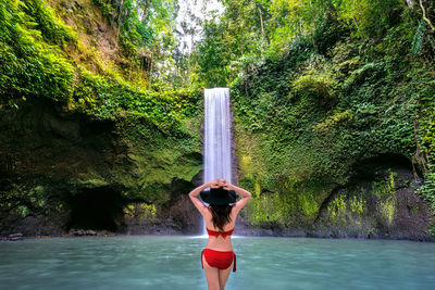 Rear view of woman standing by waterfall