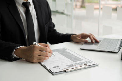 Midsection of man using laptop on table