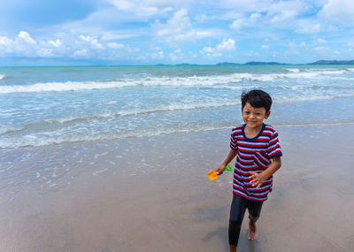 Full length of boy on beach against sky