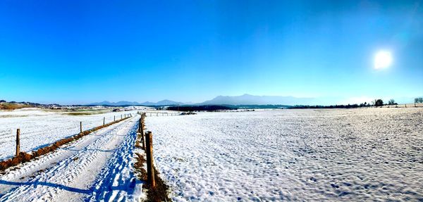 Snow covered road against clear blue sky