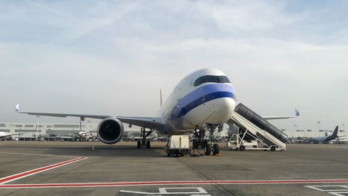 Airplane on airport runway against sky