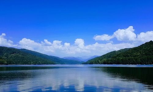 Scenic view of lake and mountains against blue sky