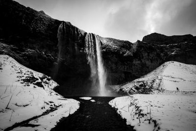 Scenic view of waterfall against sky during winter