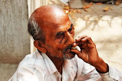 Mature man smoking beedi on footpath