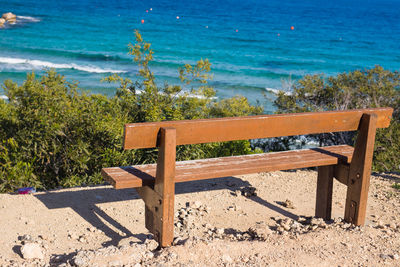 Empty bench on beach by sea