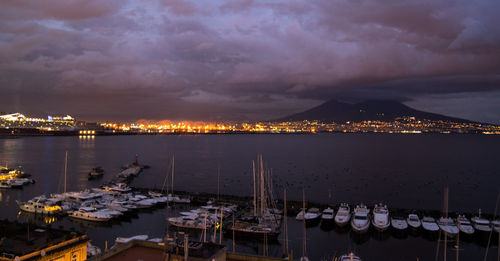 Panoramic view of illuminated city by sea against sky