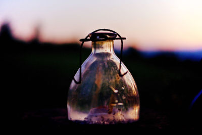 Close-up of illuminated lamp on field against sky at sunset