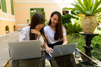 Female friends using laptop outdoors