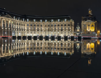 Reflection of illuminated building in city at night