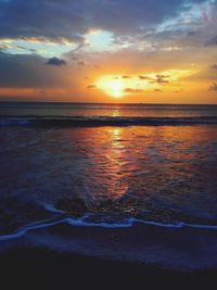 Scenic view of sea against dramatic sky during sunset