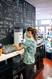 Young woman wearing mask working in cafe