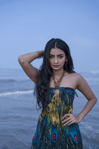 Beautiful woman sitting on field against sky