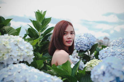 Portrait of beautiful woman against white flowering plants