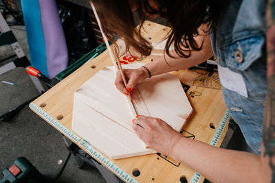 High angle view of woman measuring wood in workshop