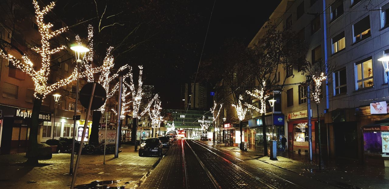 ILLUMINATED STREET BY BUILDINGS AT NIGHT