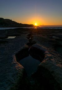 Scenic view of beach against clear sky during sunset