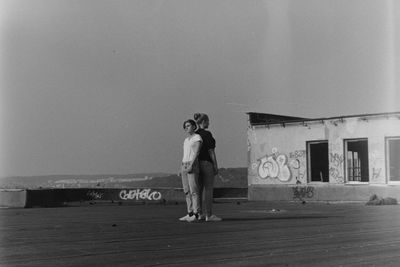 Woman standing by wall against sky