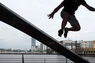 Low angle view of man jumping on bridge