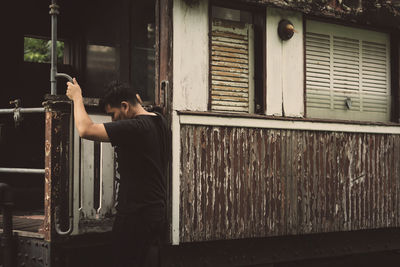 Man standing by window of building