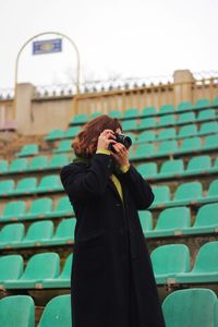 Woman photographing while standing at stadium