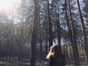 Woman standing by trees in forest