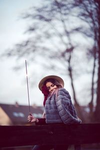 Woman wearing warm clothing while holding sparkler in city