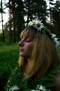 Portrait of young woman with red flower in sunlight