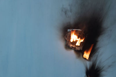 Close-up of burning candles on wood against wall