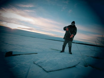 Full length of man standing on snow against sky during sunset