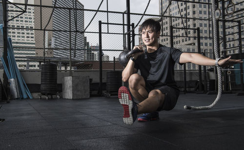 Man training with kettle bell at rooftop gym in bangkok