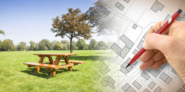 Digital composite image of architect drawing blueprint and park