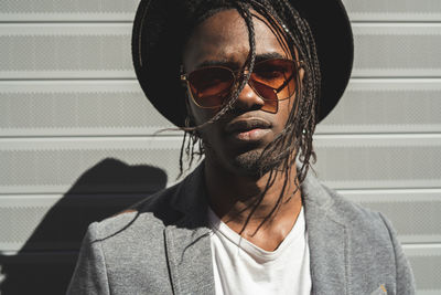 Portrait of young man wearing hat standing against shutter