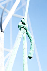 Low angle view of rope tied on metal against sky