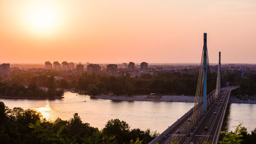 Scenic view of river by buildings against sky during sunset