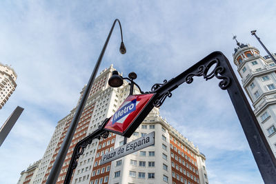 Low angle view of street light by building against sky