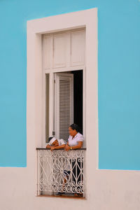 Rear view of woman sitting on table against window