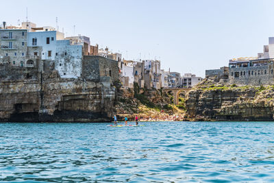 Buildings by sea against clear sky