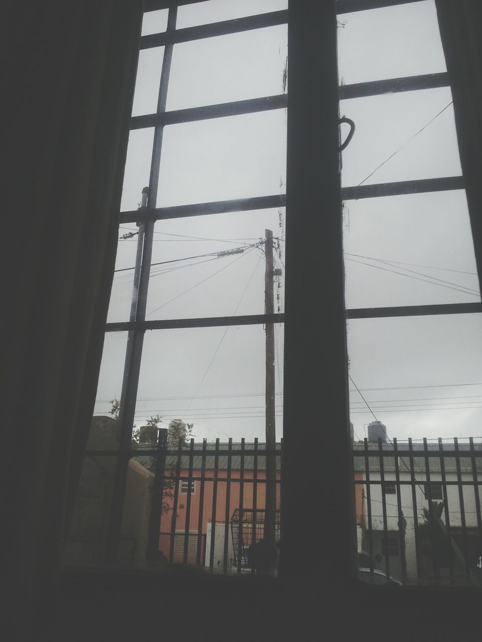 indoors, window, glass - material, built structure, architecture, low angle view, sky, transparent, silhouette, building exterior, cloud - sky, day, glass, no people, power line, building, electricity, cloud, electricity pylon, modern